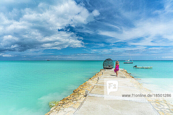 Woman walking on jetty towards a luxury gazebo over Caribbean Sea
