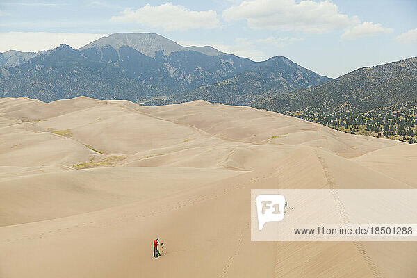 Senior couple explore sand dunes below mountains