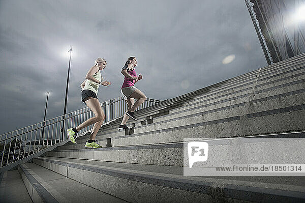 Two women jogging on staircases during dawn  Bavaria  Germany