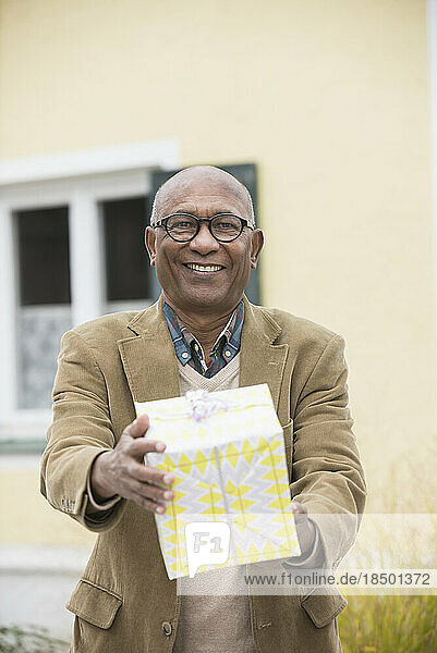Black senior man giving birthday gift and smiling  Bavaria  Germany