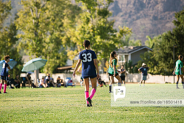 Back of girl soccer player walking on the field