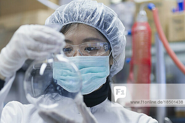 Young female scientist examining flask in a laboratory  Freiburg im Breisgau  Baden-Württemberg  Germany