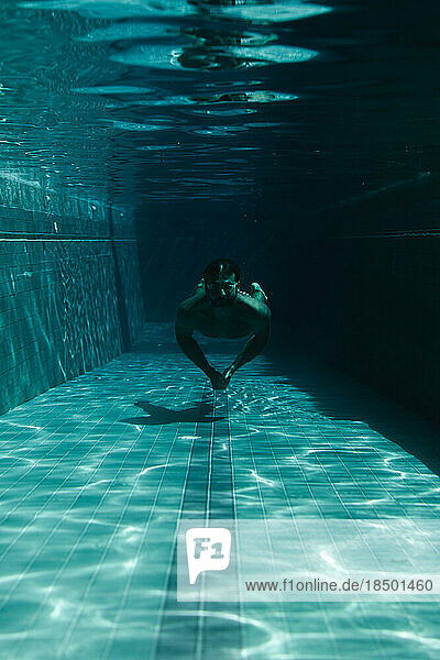 Man swimmer in the pool underwater.