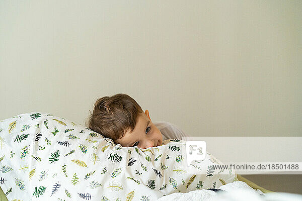 Happy little child boy in pajamas  in bed in the bedroom with to