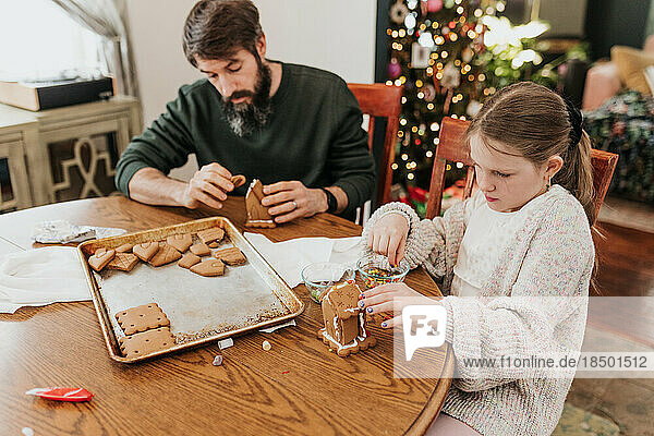 Father and daughter work together to build gingerbread house