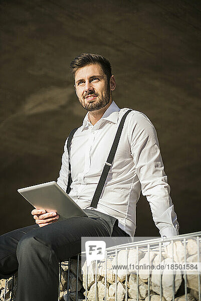 Businessman sitting and working on digital tablet  Munich  Bavaria  Germany