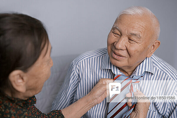 Senior woman tying her husband's tie