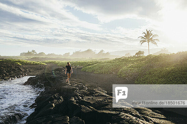 A girl is walking on lava rocks near the ocean  Big Island  Hawaii.