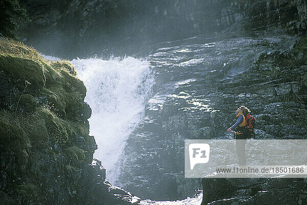 A woman hiker standing near waterfall.