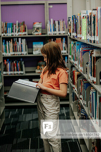 young girl reading a picture book in a library