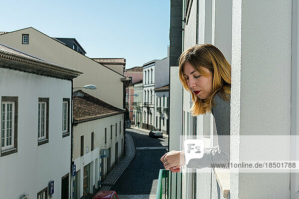 Young woman looking through the window at the city of Sao Miguel