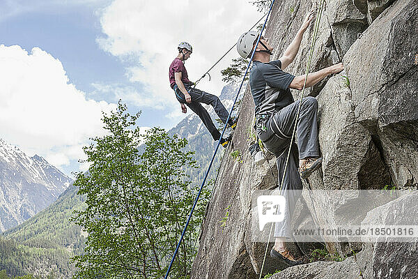 Two male rock climbers scaling a rock face at Oberried climbing garden  Otztal  Tyrol  Austria