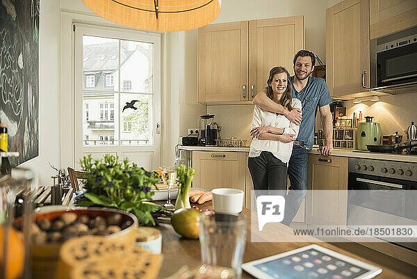 Man hugging his wife in the kitchen  Munich  Bavaria  Germany