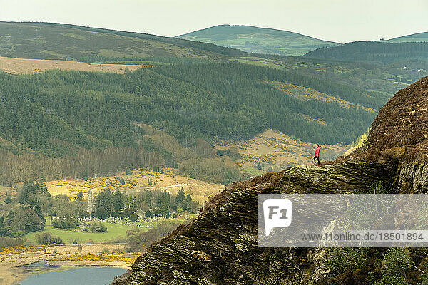 Woman on the mountaintop admiring the view of the lake in Glendalough