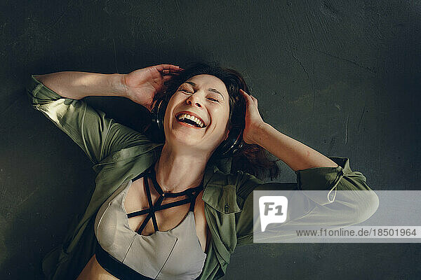 Portrait of a laughing woman with closed eyes in headphones  top view
