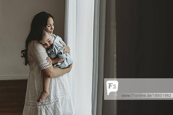 Young pregnant mother cuddling with young son in natural light studio