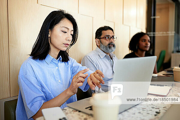 Businesswoman checking time while sitting with laptop in cafe