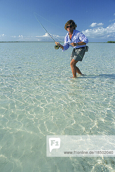 A saltwater fly-fisherman casts to a fish in shallow water.