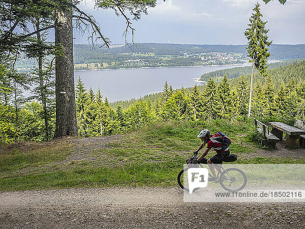 Mountain biker cycling by lake in the background near Schluchsee  Baden-Württemberg  Germany