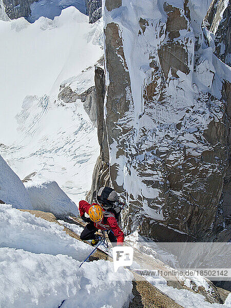 An alpinist climbs past snow and ice on the steep north face of Cerro Torre.