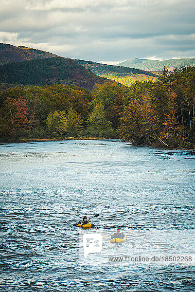 Two paddlers going down river with fall foliage
