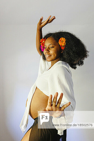 A pregnant woman dances with flowers in her hair