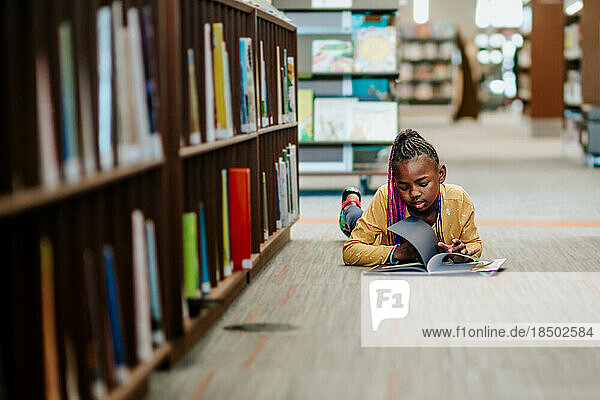 Young Black girl reading library book