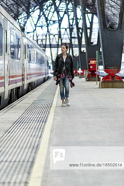 Walking woman in a leather jacket on the railway departure platform