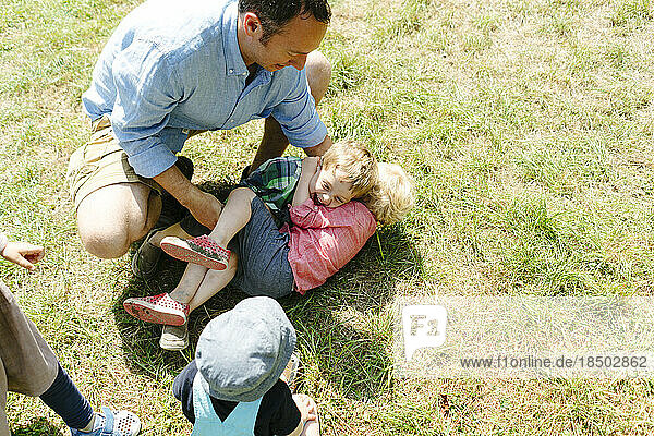 View from above of a dad and two children playing in the grass