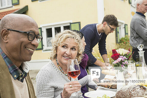 Senior woman smiling with wine glass and enjoying outdoor party with her family and friends at farmhouse  Bavaria  Germany