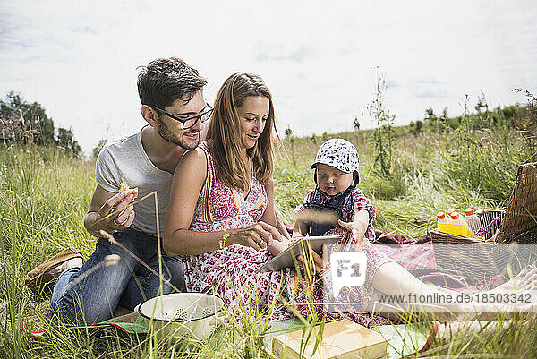 Family using digital tablet on meadow in the countryside  Bavaria  Germany