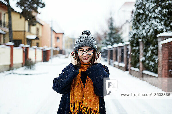 woman in yellow scarf and blue coat in middle of snowy street