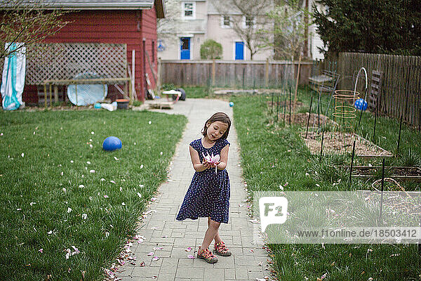 A little girl admires a large pink flower in her hands