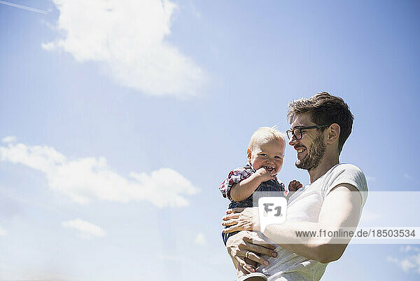 Happy man carrying his son against sky  Bavaria  Germany