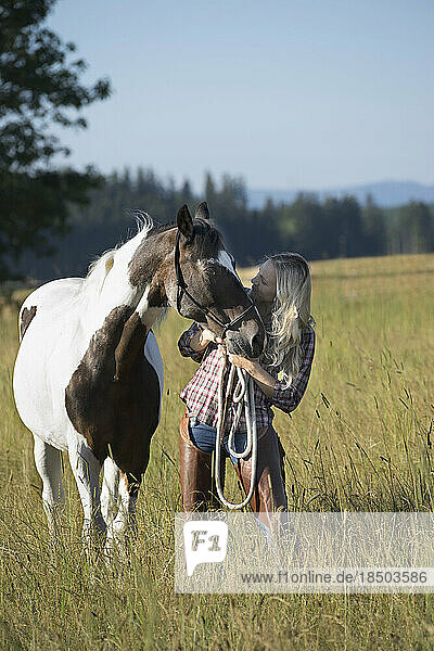 Mid adult woman standing with her horse on meadow  Bavaria  Germany