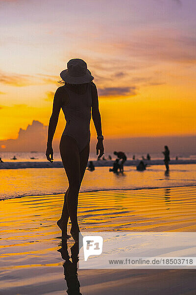Woman in a panama hat on the ocean beach. Sunset in Bali.