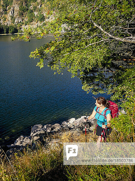 Women hiker passing by lakeside at Lac Blanc  France