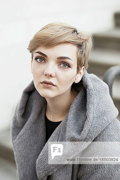 woman with short stylish hairstyle in gray coat on a white background