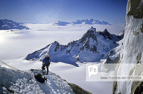 A mountaineer climbs onto a ridge on Cerro Torre's northwest face  with Cerro Rincon  Volcan Lautaro and the Continental Iceca
