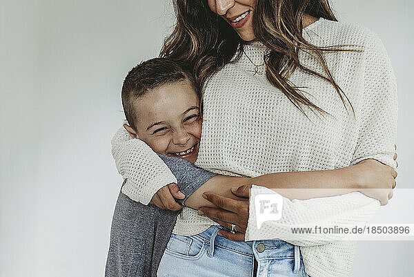Close up view of son being hugged by mother and laughing in studio