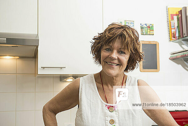 Portrait of a senior woman standing in the kitchen and smiling  Munich  Bavaria  Germany