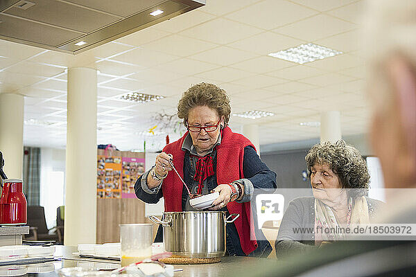 Senior woman filling and portioning the dessert in bowls at rest home