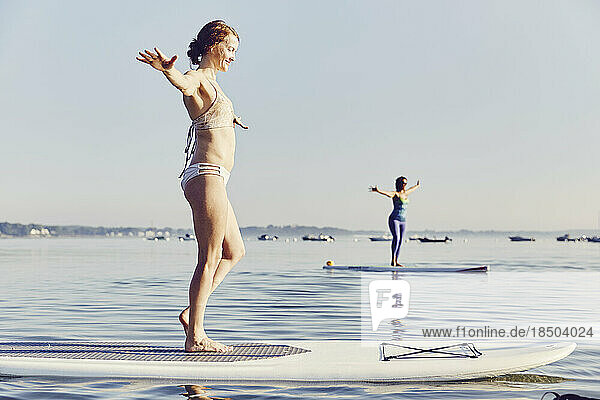 Two women doing yoga on SUP boards early in the morning