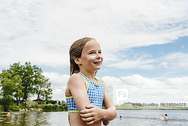 Little girl takes swim break on shore of lake during summer
