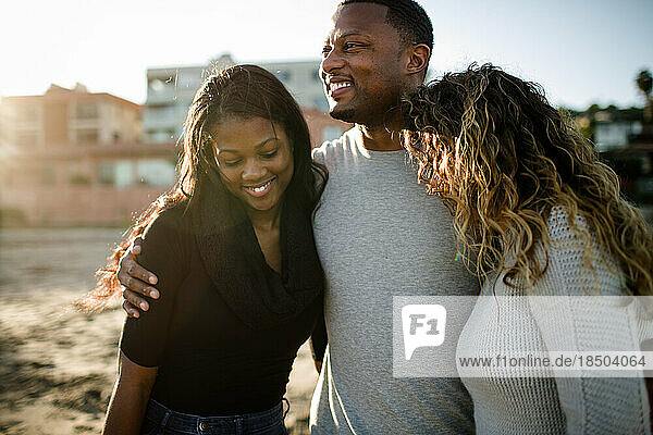 Blended family embracing and smiling on beach at sunset