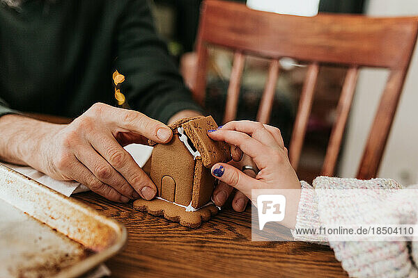 Father and daughter work together to build gingerbread house