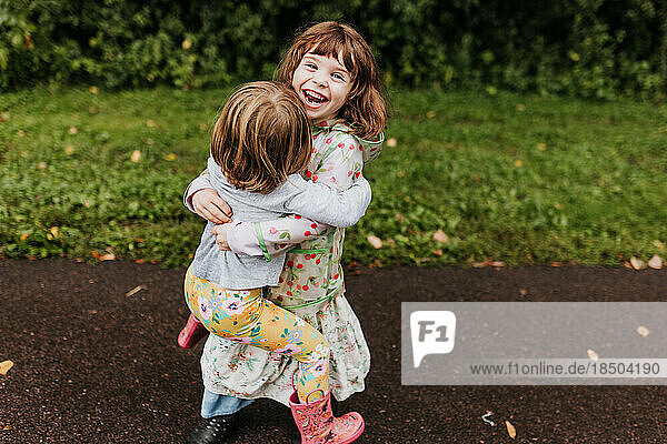 Sisters laugh and play along walking trail on a cloudy fall day