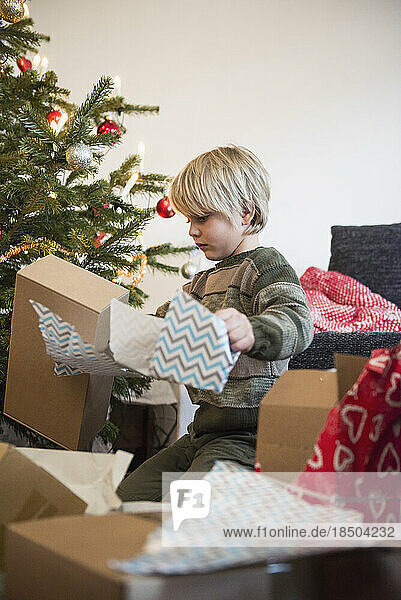 Young boy opening Christmas gift at home