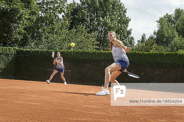 Two women playing tennis on a sunny day  Bavaria  Germany