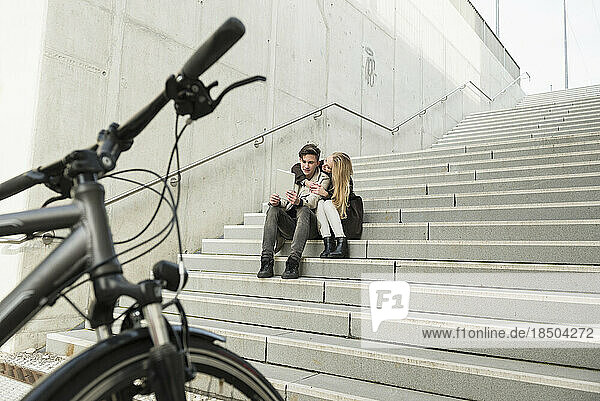 Young couple sitting on stairs and using a digital tablet  Munich  Bavaria  Germany